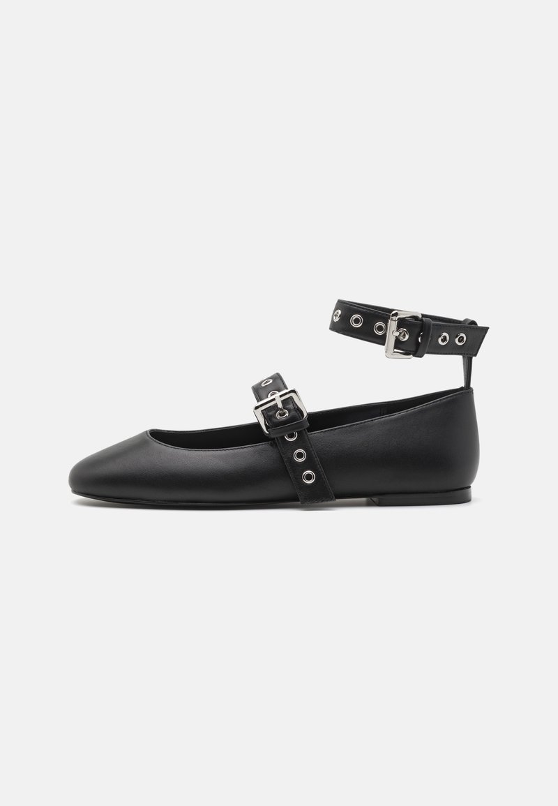 Chaussure plate noire à bout arrondi, bride à boucle réglable sur le cou-de-pied et bride de cheville avec œillets métalliques et boucle.