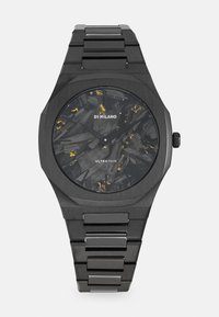 Montre noir ultra-fine avec un cadran texturé foncé et des accents dorés, boîtier octogonal et bracelet en acier inoxydable.