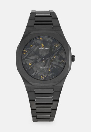 Crni ultra tanki sat s teksturiranim tamnim brojčanikom i zlatnim akcentima, oktagonalnim kućištem i narukvicom od nehrđajućeg čelika.