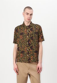 Camisa de manga corta con un patrón de leopardo en verde, negro y naranja, que presenta un frente abotonado y un bolsillo en el pecho.