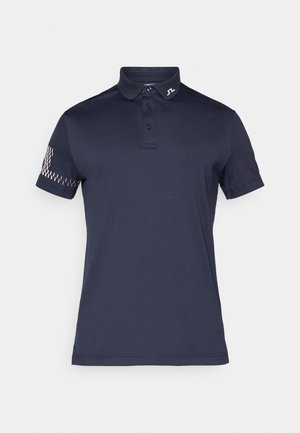 Temno modra polo majica s ovratnikom, zapenjanjem na tri gumbe in kratkimi rokavi. Ima teksturiran vzorec na levem rokavu in logo na ovratniku.