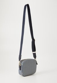 Borsa a tracolla a righe blu navy e bianche con chiusura a zip, forma rettangolare, texture in tessuto e tracolla regolabile con dettagli in oro.