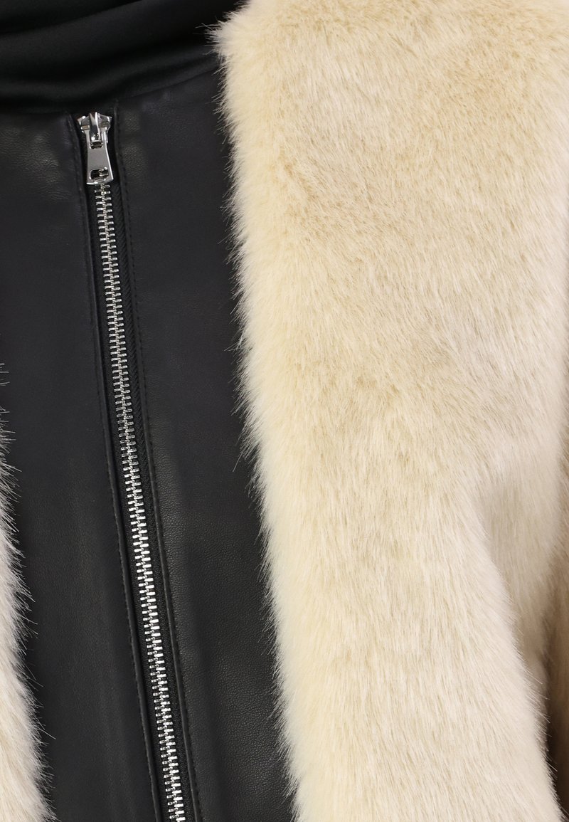 Czarna skórzana kurtka z kremowym kołnierzem z futra syntetycznego; posiada srebrny zamek błyskawiczny z przodu, z kontrastującą fakturą między materiałami.