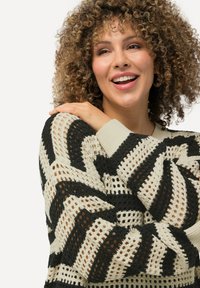 Maglione a maglia con un motivo a righe ondulate in nero e crema, caratterizzato da una lavorazione aperta e texture, con polsini a costine, che offre una vestibilità rilassata.