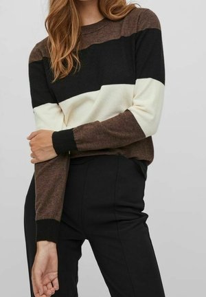 Pull en maille avec des rayures horizontales marron, noir et blanc. Manches et encolure ajustées. Porté avec un pantalon noir. Texture lisse.