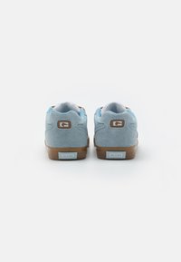 Light blue suede sneakers with a brown rubber sole, gray mesh tongue, and a white logo patch on the heel. Rounded design with cushioned collar.