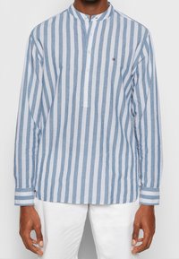 Camicia a maniche lunghe a righe in cotone leggero blu chiaro e bianco, con colletto stondato, patta dei bottoni e dettagli a righe contrastanti sulle maniche.
