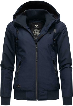 Marineblauwe hoodie met een ritssluiting aan de voorkant, meerdere zakken en geribde manchetten. Heeft een zachte textuur en een contrasterende binnenvoering.
