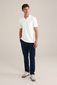 Bílá polo košile s krátkým rukávem a V-výstřihem, kombinovaná s námořnickými kalhotami a světle šedými teniskami s bílými detaily a gumovou podrážkou.