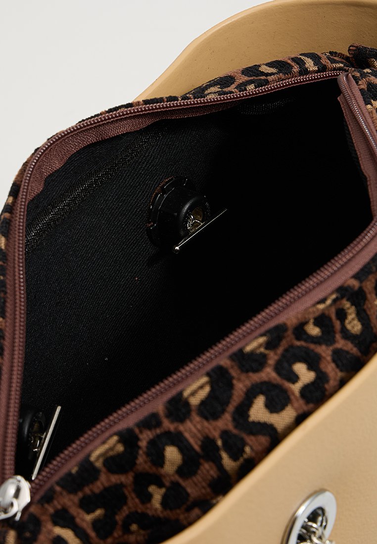 Beżowa torebka z brązowym wnętrzem w leopardzi wzór. Posiada zamek błyskawiczny, czarną podszewkę oraz zapięcie na zatrzask wewnątrz.