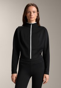 Čierna zipová bunda s dlhými rukávmi, vyrobená z textúrovaného materiálu. Má stojatý golier a kontrastný biely zips.