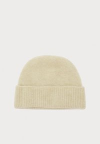 Bonnet en tricot de couleur beige clair avec une texture douce, un sommet arrondi et un poignet côtelé. Design simple adapté à diverses tenues.