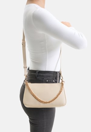 Beige Umhängetasche aus glattem Leder mit einer goldfarbenen Kettenakzent. Rechteckige Form mit weicher Textur und verstellbarem Riemen.