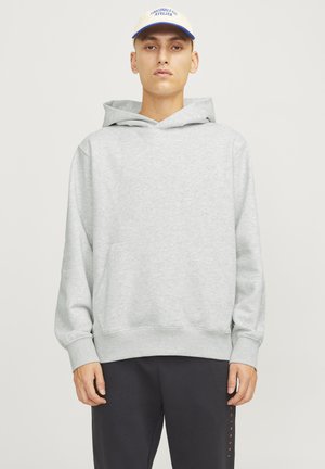 Hoodie gris en mélange de coton avec une poche kangourou et une coupe décontractée. Associé à un pantalon sombre. La casquette a une visière claire et des accents bleus.