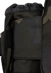 Dettaglio di uno zaino nero camouflage che mostra un tessuto texturizzato, cinturini sicuri e una chiusura superiore a coulisse per un facile accesso. Design resistente e multifunzionale.