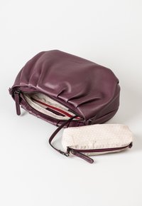 Lila Ledertasche mit gerafftem Design, ausgestattet mit einem Reißverschluss, beigen Innenfutter und einem kleinen gemusterten Täschchen.