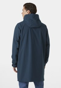 Giacca impermeabile blu marina con cappuccio, maniche lunghe e vestibilità morbida. Tessuto liscio, design minimalista e polsini regolabili.