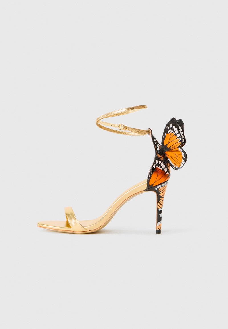 Złote sandały na wysokim obcasie z paskiem na kostce i motywem motyla w kolorze pomarańczowym, czarnym i białym na obcasie oraz tylnym pasku.