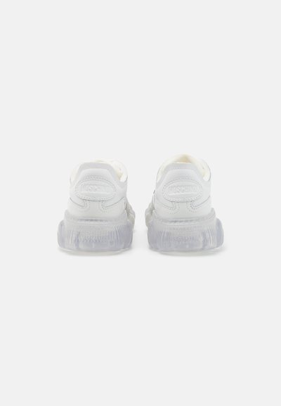 White sneakers with a textured leather upper, a chunky translucent sole, and embossed branding on the heel and upper side.