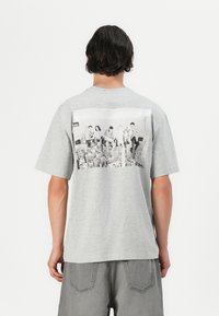 Grå bomuld t-shirt med et stort sort-hvidt fotoprint på ryggen, korte ærmer og en afslappet pasform.
