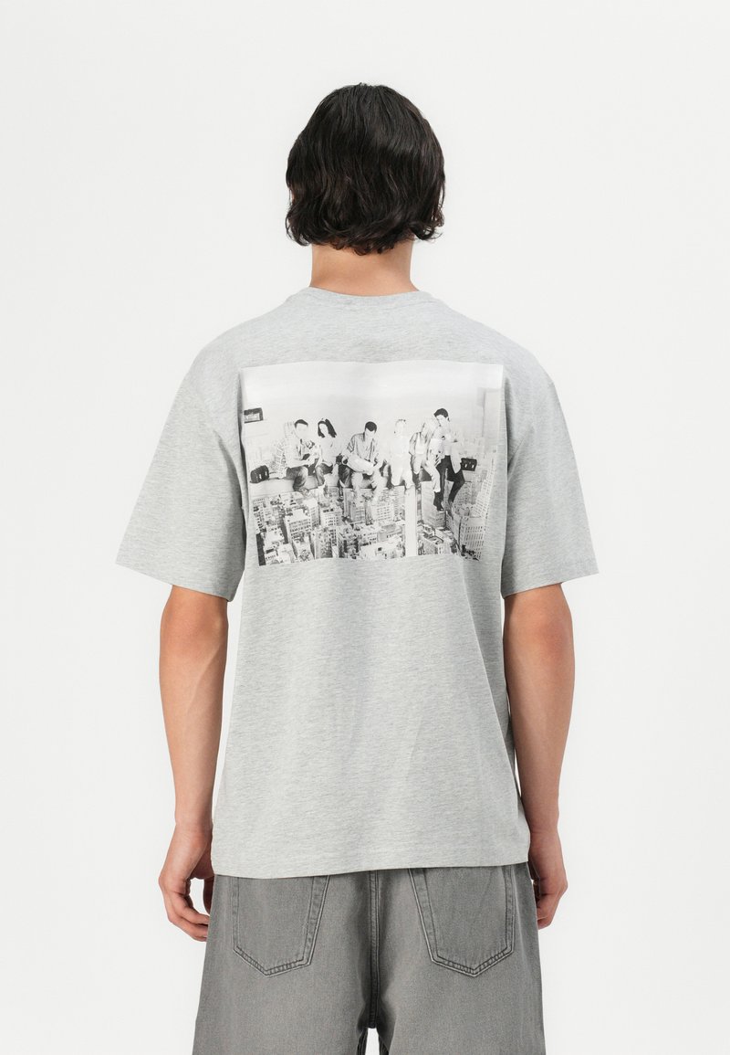 Grå bomuld t-shirt med et stort sort-hvidt fotoprint på ryggen, korte ærmer og en afslappet pasform.
