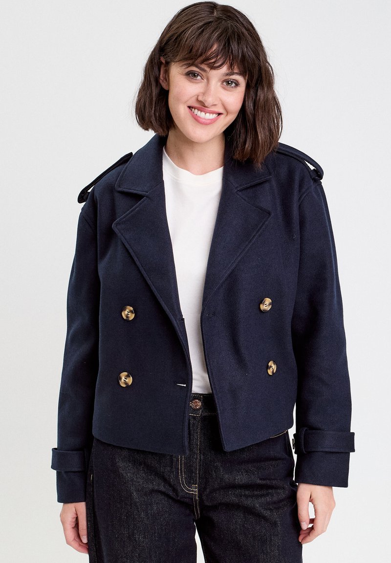 Veste en laine bleu marine croisée avec des boutons dorés, revers en pointe et épaulettes ; design court avec des manches à revers.