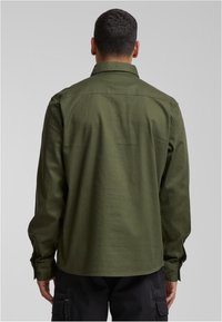 Camisa de manga larga de color verde oliva con cuello estándar, puños con botones y dobladillo recto. Fabricada con tejido liso y ligero.