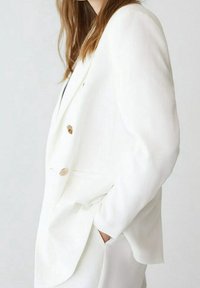 Witte blazer met een dubbelbreasted ontwerp, op maat gesneden pasvorm en accenten van goudkleurige knopen, gemaakt van een zachte, textuurrijke stof.