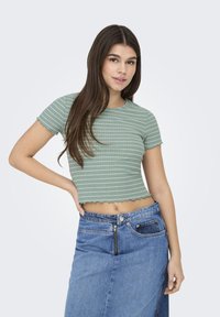 Crop top court rayé vert avec un ourlet festonné, associé à une jupe en denim avec une fermeture éclair avant et des détails de poche.