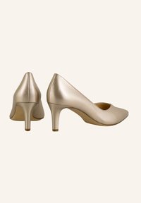 Chaussures à talons hauts en cuir doré avec un bout pointu, présentant une texture lisse et un talon fin. Design minimaliste sans accents visibles.