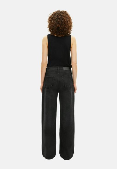 Jeans de pierna ancha negros con una cintura alta, que presentan una textura suave, dos bolsillos traseros y un sutil parche de cuero en la cinturilla.