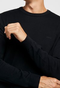 Black long-sleeve T-shirt made from cotton with a ribbed crew neckline and fitted cuffs. Features a subtle "Esprit" logo on the chest.