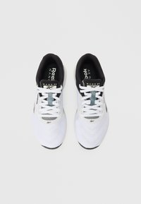 Valkoinen Reebok Nano XV -kengät, joissa on mustat sisäosat ja valkoiset nauhat, näkyvät ylhäältä valkoista taustaa vasten.