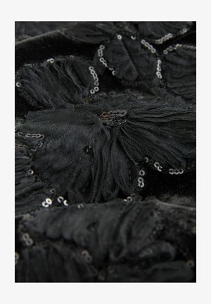 Tejido negro texturizado con un diseño de aplicación floral en capas y pailletes esparcidos por todo el material, creando un efecto brillante.