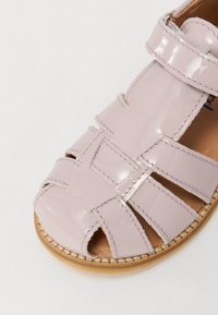 Sandalo in vernice lilla chiaro con punta aperta, design intrecciato e cinturino con fibbia, suola in pelle naturale.