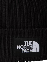 Μαύρη πλεκτή σκούφος με ριμπ υφή, με εμφανές λευκό λογότυπο "THE NORTH FACE" και κυρτό λευκό διακοσμητικό στοιχείο.