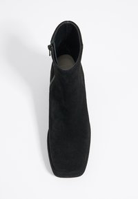 Botín de ante negro con un diseño elegante, puntera cuadrada y cremallera lateral para el cierre. Textura suave y estética minimalista.