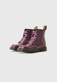 Botas de tobillo con textura de piel de serpiente púrpura y cordones rosa, con una suela negra gruesa y etiquetas de marca amarillas en la parte trasera.