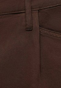 Tissu en coton marron avec une texture lisse, comportant une poche sur le côté et une taille. Les coutures sont visibles le long des bords.