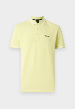 Šviesiai geltonas medvilninis polo marškinėliai su klasikiniu apykakle, dviem mygtukais ir baltais dryžiais ant rankovių. Su juodu logotipu.