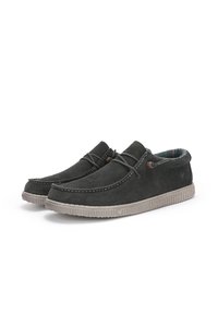 Mocassins en daim gris foncé avec une semelle en caoutchouc beige. Présentent un design surpiqué, un détail à lacets et une doublure intérieure texturée.