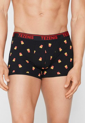 Torso masculino con bóxers negros con cintura roja y estampado de patatas fritas amarillas y rojas, de pie con los brazos relajados a los lados.
