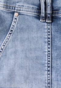 Helles blaues Denim-Gewebe mit glatter Textur. Verfügt über einen Metallknopf und kontrastierende Nähte entlang der Taschen- und Nahtbereiche.