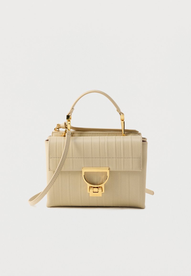 Μπεζ τσάντα χειρός με κάθετη ραβδωτή υφή, μεταλλικά στοιχεία σε χρυσή απόχρωση, χειρολαβή στην κορυφή και αποσπώμενο ιμάντα ώμου. Κλείνει με φερμουάρ.