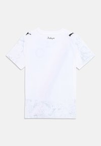 Vit kortärmad t-shirt med ett texturerat, mönstrat nederkant och svarta Puma-accenter på axlarna, samt "KidSuper"-logotyp vid nacken.