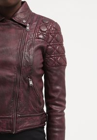 Giubbotto da motociclista in pelle borgogna con dettagli trapuntati sulle spalle, tasche con zip e un design slim fit.