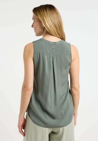 Blusa senza maniche di colore verde salvia con scollatura arrotondata, piega dietro e discreto logo; tessuto morbido e leggero con una superficie liscia.