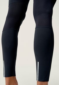 Námořnické sportovní legíny s hladkou texturou, reflexními detaily, jemným panelovým designem a těsným střihem kolem lýtek.