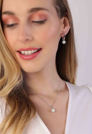 Zilveren oorbellen met een ronde pareldruppel en een zilveren kettinghanger met een iriserende steen aan een dunne ketting.