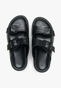 Černé kožené sandály se dvěma širokými popruhy s nastavovacími přezkami, texturovaným povrchem a tvarovanou stélkou pro komfort.